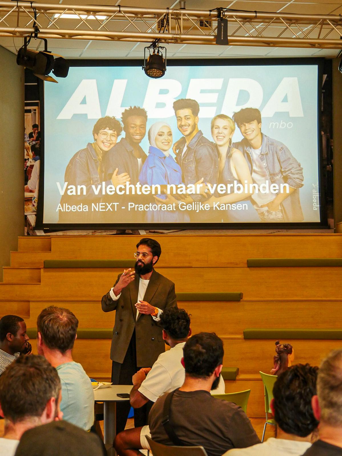 Presentatie 'Van vlechten naar verbinden' voor een zaal vol papa's